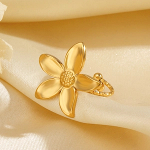 Exquisite gold stainless steel flower ear cuff placed on elegant champagne silk fabric