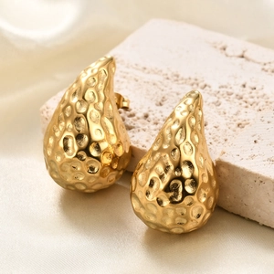 Détail macro de boucles d'oreilles gouttes dorées de 33mm avec texture martelée
