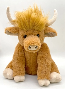 Macro shot of Highland Cow plush toy with golden shaggy fur, cream horns and soft texture