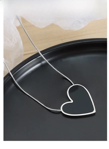 Detail view of a silver titanium steel heart necklace draped over a black display dish