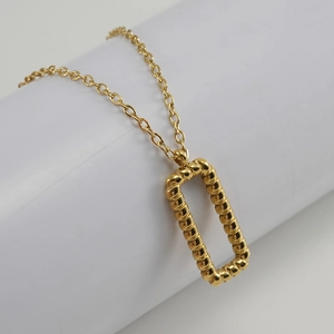 Macro view of gold-plated twisted rectangle pendant on a classic link chain necklace