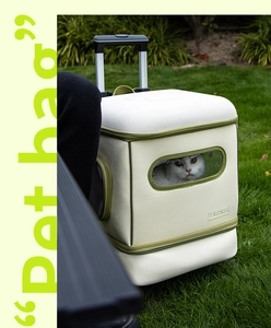 Close-up of beige and green pet carrier with telescopic handle on a grassy lawn