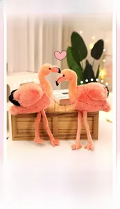 Vue détaillée de deux flamants roses en peluche dans un cadre chaleureux avec guirlandes