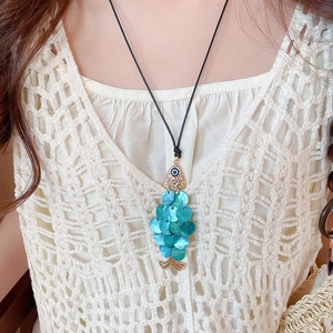 Detail of fish pendant necklace with blue shell and gold metal on black cord chain
