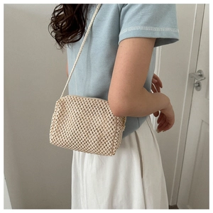 Detail of mini straw woven crossbody bag featuring beige texture and top zipper closure