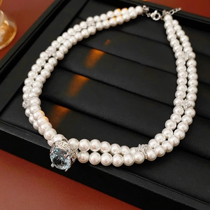 Détail d'un collier de perles à double rang avec une pierre bleue sur plateau noir