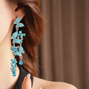 Detail of silver drop earrings featuring turquoise butterflies and blue crystal accents