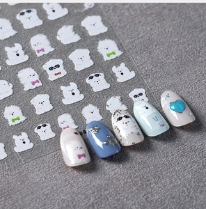 Macro shot of 5D cute white puppy nail stickers and sample nails on a textured grey background