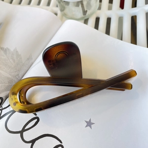 Detail of amber tortoiseshell claw clip on artistic white paper with star patterns