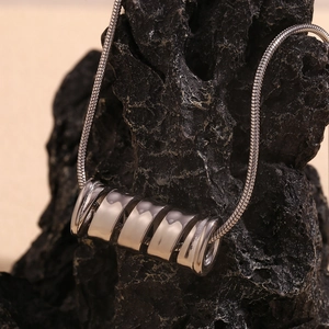 Detailed close-up of a silver spiral spring pendant on a sleek snake chain necklace