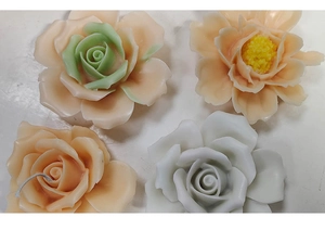 Detailed top view of four realistic rose and peony floral candles in various colors