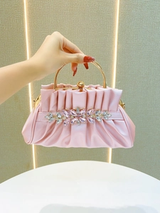 Detail of pink pleated clutch bag with golden ring handle and crystal floral ornament