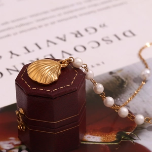 Detailed shot of 18K gold shell pendant necklace with pearls on a vintage jewelry box
