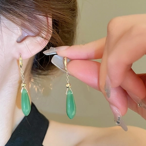Close-up of gold plated teardrop emerald glass earrings showing drop length and texture