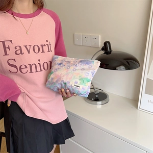 Handheld view of a floral cotton makeup bag featuring a vintage botanical print