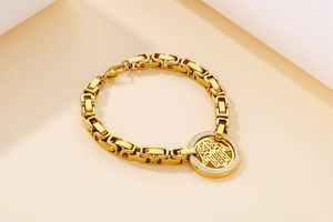 Detailed close-up of gold Hamsa hand pendant with micro-pave crystals on link bracelet