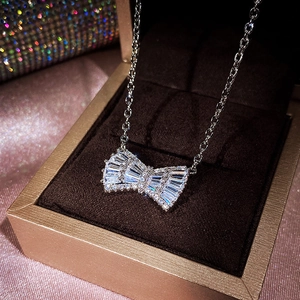 Close-up of sparkling silver bow pendant with clear zircons in a luxury jewelry box
