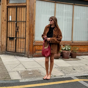Veste en daim marron assortie d'un sac rouge et haut noir dans un style urbain chic