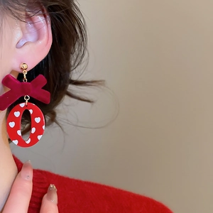 Gros plan de boucles d'oreilles nœud en velours rouge avec breloque cœur pour un look festif
