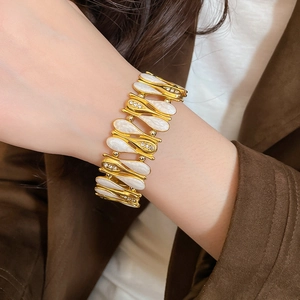 Detail of a vintage gold bracelet with white teardrop enamel and sparkling rhinestones