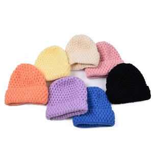 Detail view of colorful knit beanies in orange, yellow, pink, and blue showing thick texture