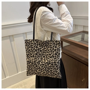 Lifestyle view of large leopard print canvas tote bag with black straps on a model