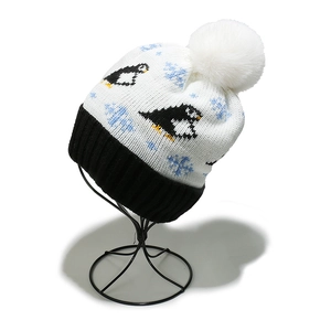 Detail of penguin jacquard knit hat with fluffy white pom-pom and thick fleece lining