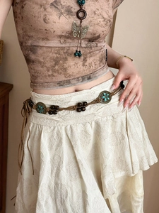 Close-up of bohemian woven waist chain with wooden beads and floral metal buckles