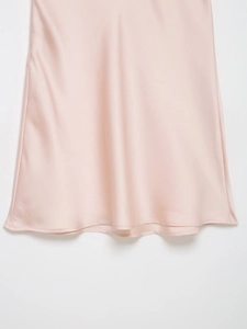 Gros plan sur l'ourlet lisse de cette robe en satin rose clair au fini soyeux