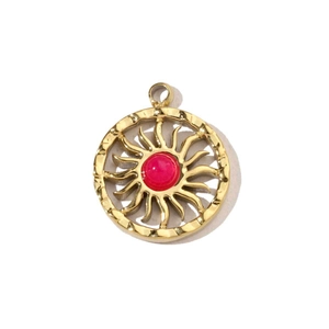 Dettaglio di un ciondolo a forma di sole dorato 14k con castone in gemma rossa vibrante