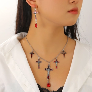 Detail of silver cross necklace and earrings with red enamel and teardrop crystals