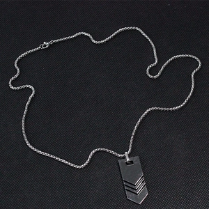 Geometric silver stainless steel arrow tag pendant necklace on black textured background