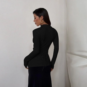 Détail du design noué au dos sur un haut noir ajusté à manches longues pour femme