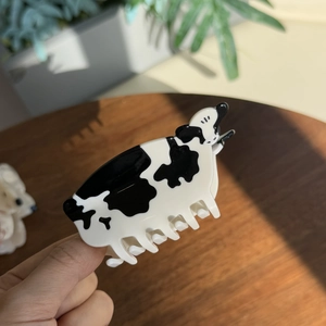 Gros plan sur la pince à cheveux motif vache en acétate noir et blanc brillant