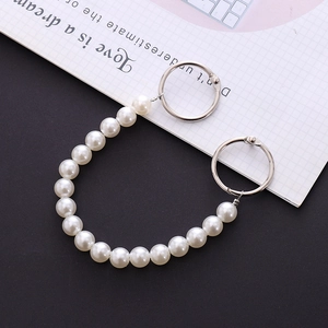 Elegant white pearl shoe chain and bag handle with silver metal rings on a book