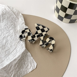 Macro view of checkered claw clip with unique wavy shape on leather display tray