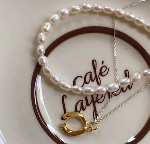 Detail of irregular natural pearls and gold horseshoe pendant on a ceramic plate