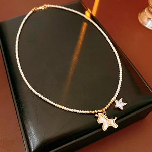 Detail of pearl necklace featuring a gold unicorn pendant and a sparkling star charm