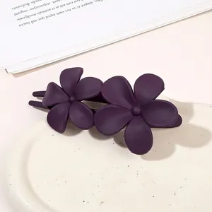Close-up of matte dark purple double flower hair clip on elegant ceramic tray