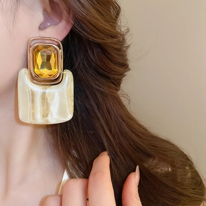 Detail of vintage square resin drop earrings with amber crystal and marble texture