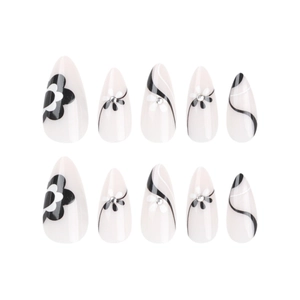 Almond press-on nails with black flower patterns, stripes, and rhinestone accents