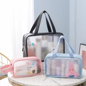 Three-piece set of transparent PVC makeup bags in pink, blue, and black on a marble table