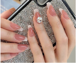 Close-up of pink nude gradient press-on nails with white French tips and crystal rhinestones