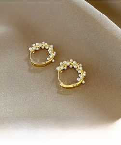Macro view of gold hoop earrings featuring embedded white pearls on silk background