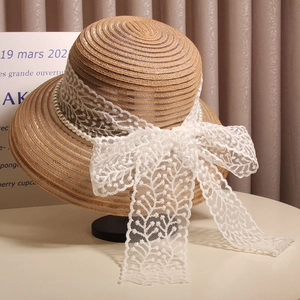 Gros plan d'un élégant chapeau de paille avec nœud en dentelle et bordure en perles