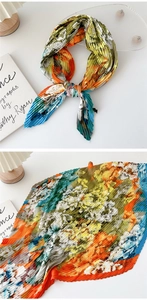 Macro shot of accordion pleated silk scarf featuring artistic oil painting floral patterns