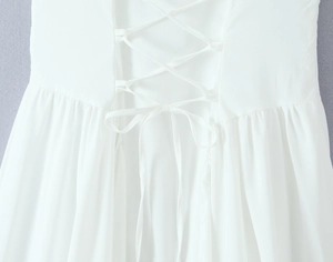 Détail de la robe blanche présentant un laçage croisé élégant au dos et des plis