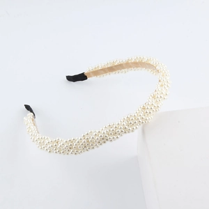 Close-up of elegant gold woven headband with white pearls and protective black ends