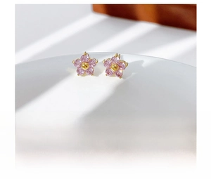 Detail of pink crystal flower earrings on white ceramic bowl edge in soft natural light