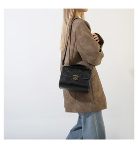Detail of vintage black embossed floral shoulder bag with an antique bronze metal lock